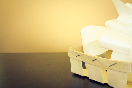 Beautiful white bow in an handmade little basket made from wood on a dark wooden table with yellow backgroundの写真素材