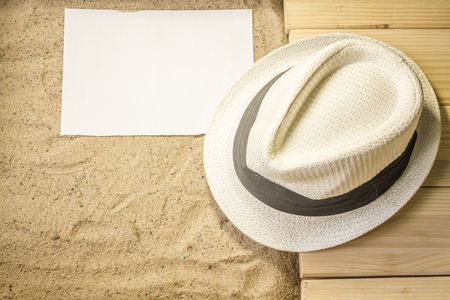 Shot to a few wooden planks, sand, a few summer clothing articles and a white plain piece of paperの写真素材