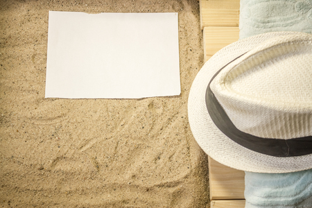 Shot to a few wooden planks, sand, a few summer clothing articles and a white plain piece of paperの写真素材