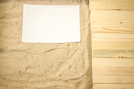 Summer beach backround made from some wooden planks, sand and a white plain piece of paperの写真素材