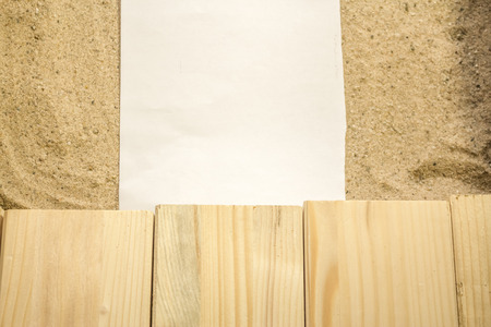 Summer beach backround made from some wooden planks, sand and a white plain piece of paperの写真素材