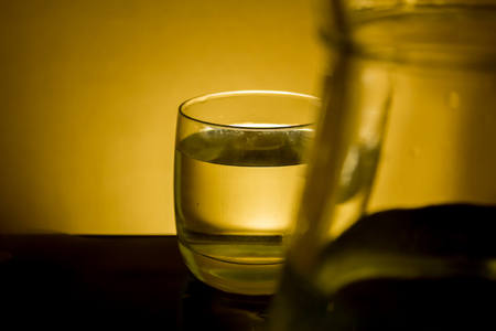 Elegant shot of a  glass of water and a pitcher on a dark backgroundの写真素材