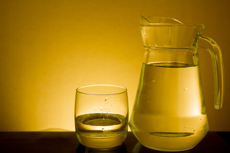 Elegant shot of a  glass of water and a pitcher on a dark backgroundの写真素材