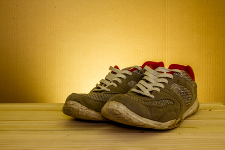 Elegant shot of  some used sport shoes sitting on a wooden table with a dark backgroundの写真素材