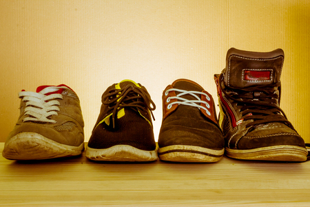 Elegant shot of  some used sport shoes sitting on a wooden table with a dark backgroundの写真素材