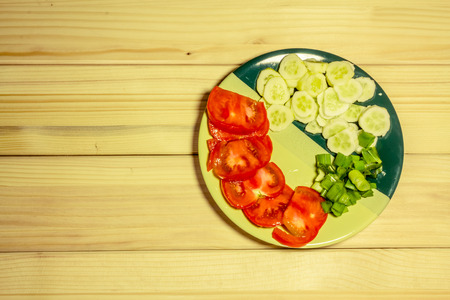 A few sliced vegetables on a plate with a wooden backgroundの写真素材