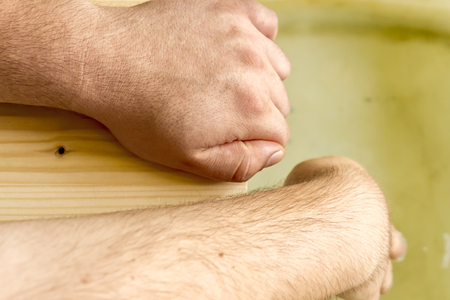 Close up shot to two hands holding to a wooden floor while one is testing the waterの写真素材