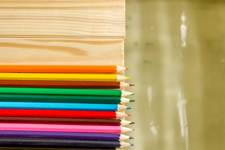 Close up shot to a few colored pencils standing on a wooden floor next to waterの写真素材