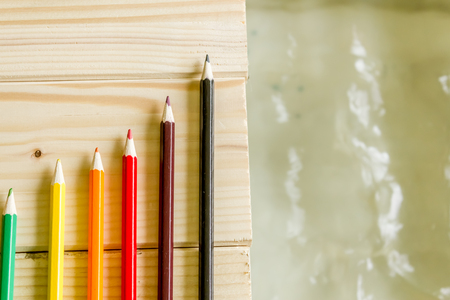 Close up shot to a few colored pencils standing on a wooden floor next to waterの写真素材