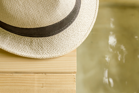 Close up shot to a fedora hat standing on a wooden floor next to waterの写真素材