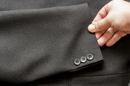 Hand holding a sleeve with a few buttons on a business suit coatの写真素材