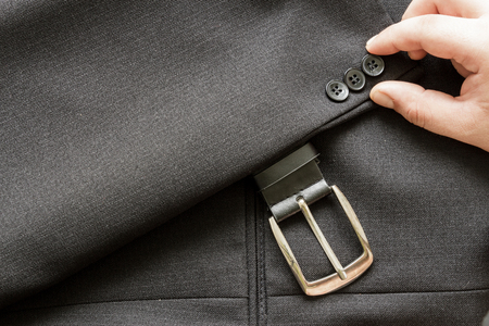 Hand doing  a few buttons on a business suit coat and leather beltの写真素材
