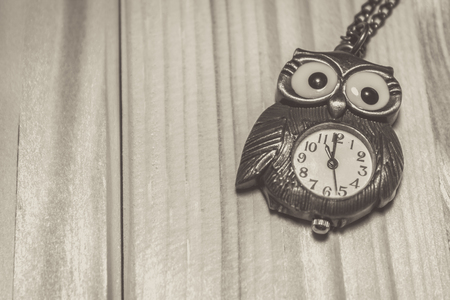 Close up shot to a vintage owl watch on a wooden tableの写真素材