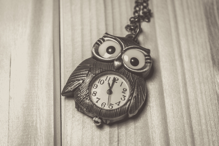 Close up shot to a vintage owl watch on a wooden tableの写真素材
