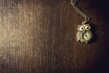 Close up shot to a vintage owl watch on a wooden tableの写真素材