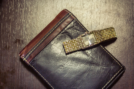 Vintage watch sitting on a leather wallet on dark wooden backgroundの写真素材