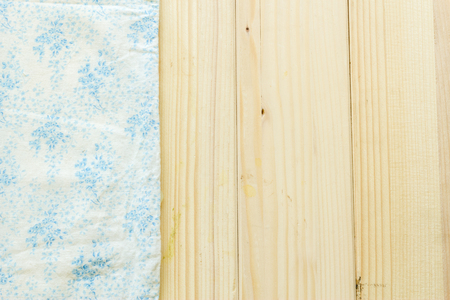 Creased cloth material fragment background with pattern on woodの写真素材