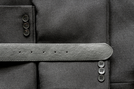 Close up of a few buttons on a business suit coat and a leather beltの写真素材