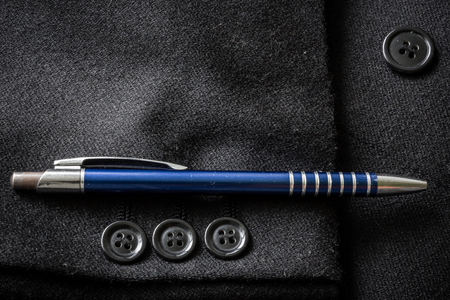 Closeup of a suit buttons and a blue metallic pen on a business coatの写真素材