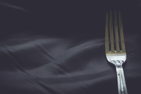 Fork on dark crumpled silk backgroundの写真素材