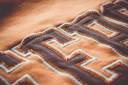 Close-up to fabric of a orange blouse with a few letters saw on it