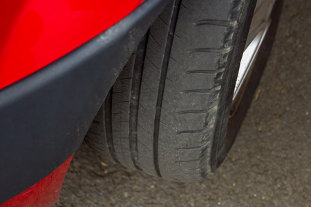 closeup to a red car's tyre on the roadの写真素材