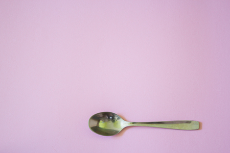 closeup to a tea spoon on light pink background with copyspace for backgroundの写真素材