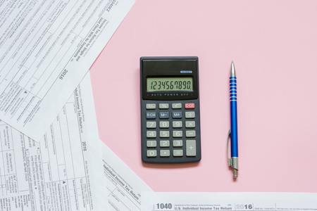 US tax form 1040 with calculator and pen. tax form. law document usa. pink background. mathematics business concept.の写真素材
