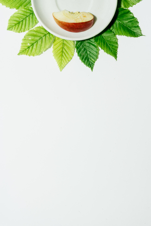 Apple slice on a plate over leaves and white background. Vertical cover, banner, flyer, leaflet, page designの写真素材
