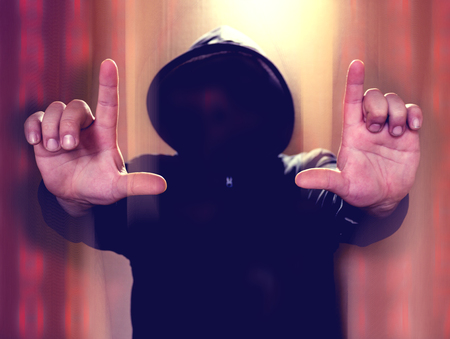 Hacker without face holding hands in the air on distorted colorfull background. Hacking concept illustrationの写真素材