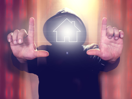 Hacker holding virtual screen with home icon. Cyber security or smart house hacking conceptの写真素材