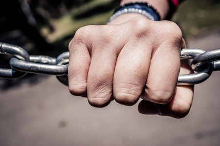 Young hand on a stainless steel chain. Youth issues concept. Conceptual image