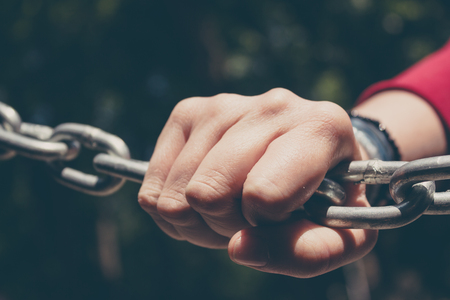 Young hand on a stainless steel chain. Youth issues concept. Conceptual imageの写真素材