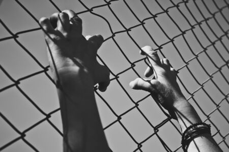 Hand holding on a chain link fence