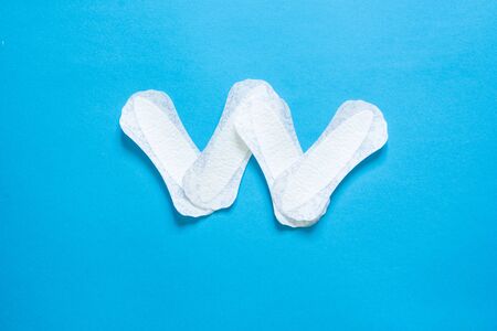 W letter made from ladies absorbents on blue background with copy spaceの写真素材