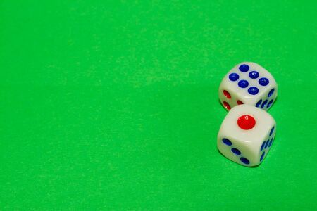 Two white dices with red and blue dots on green table. Casino gambling concept imageの写真素材