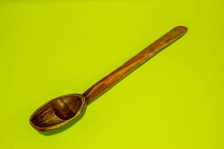 Rustic wooden spoon with long handle on green backgroundの写真素材