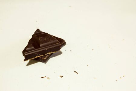 Two dark chocolate pieces with crumbs around it on white background with copy spaceの写真素材