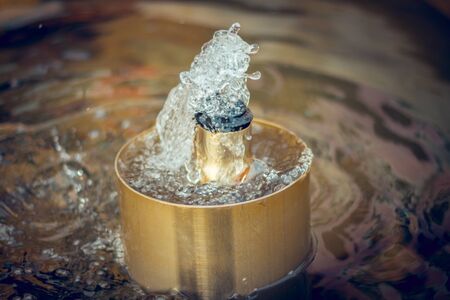 Sprinkler of a crafted fountain with water sprinkling out of itの写真素材