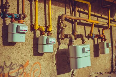 Gas meters hanged on an exterior building wall with yellow pipesの写真素材