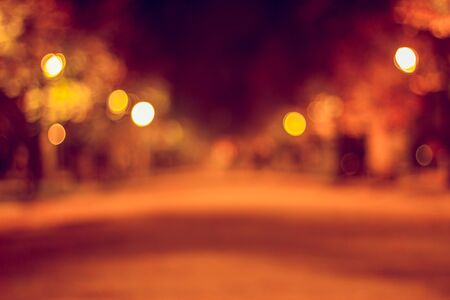 Park alley in blur at night with street lanterns lighting the path with yellow color.の写真素材
