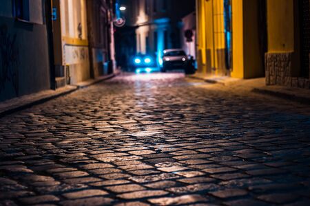 Paved road at night with a car with blue headlights turned on in backgroundの写真素材