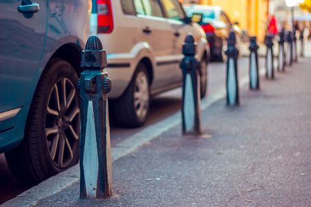 Cars parked near sidewalk delimited by street bollardsの写真素材