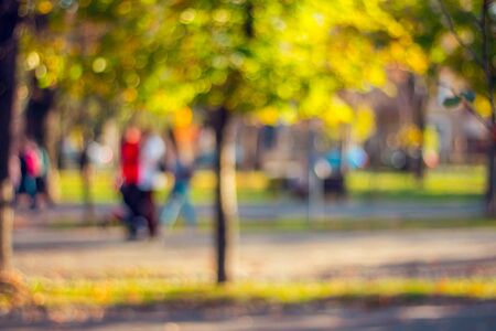 Beautiful defocused background of people walking in the park in autumnの写真素材