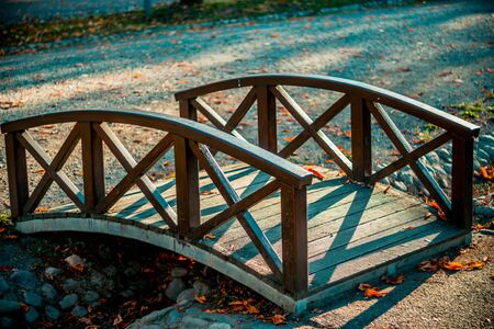 Beautiful wooden arched bridge over the river the flows in a park in a cityの写真素材