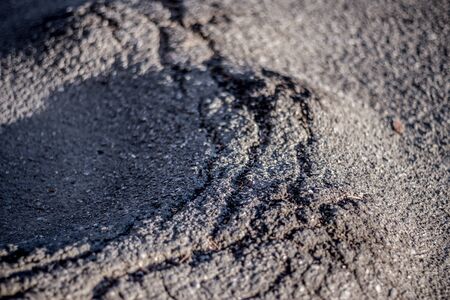 Closeup of a bad and cracked street. Asphalt texture with a rough surface grey background.の写真素材