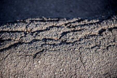Cracked road rough texture closeup. Abstract concept of a bad and damaged streetの写真素材