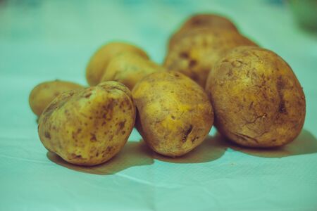 Closeup of a pile of potatoes on a  kitchen table ready to be cooked.の写真素材