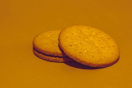 Two round digestive biscuits on a brown background stacked one on top of the otherの写真素材