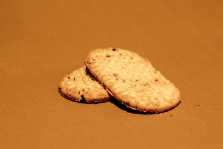 Two long round cornered digestive crackers one on top of the other on a brown paper with crumb on itの写真素材